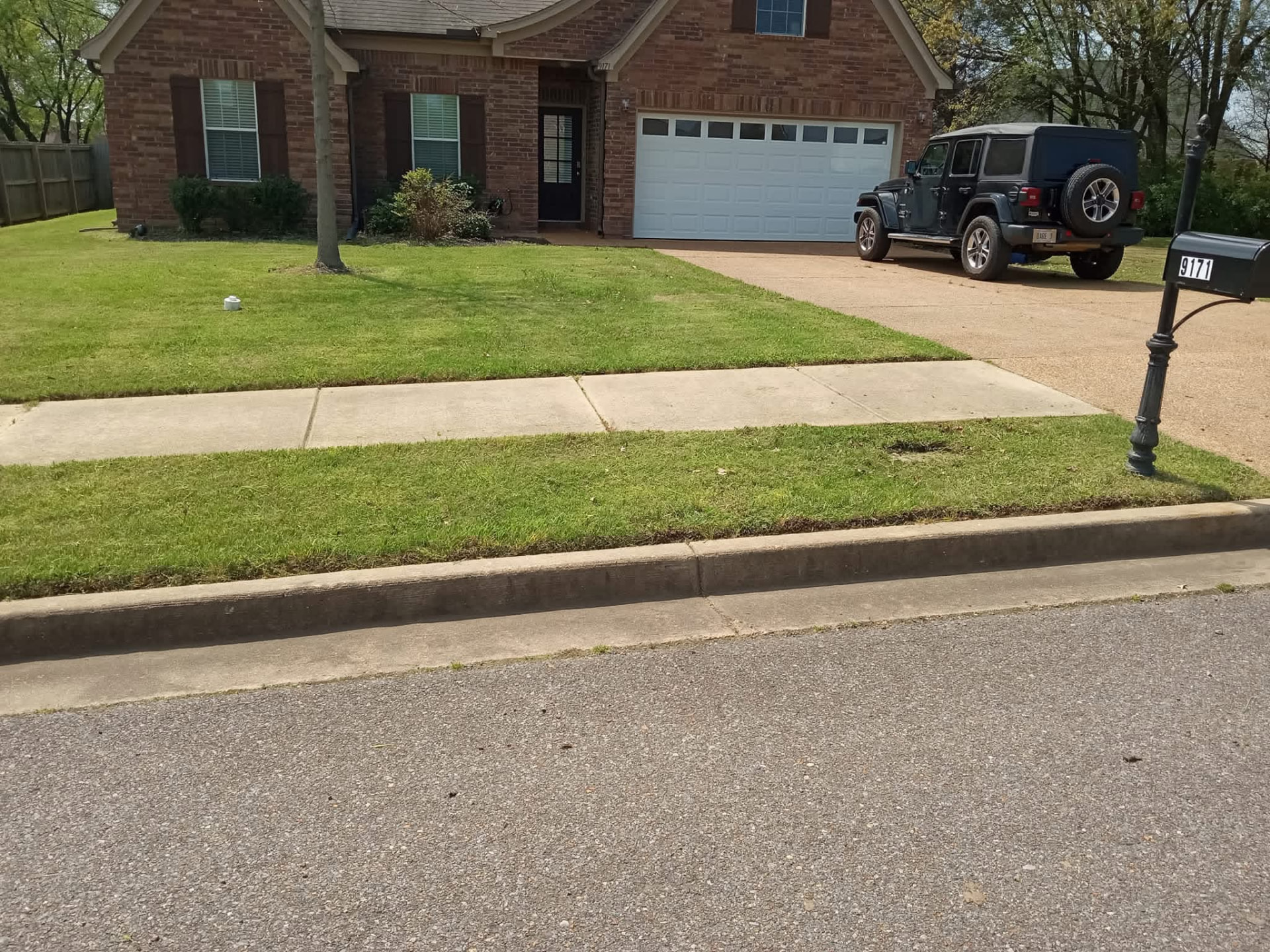 The same brick home with a freshly mowed lawn and crisp curb line after mowing